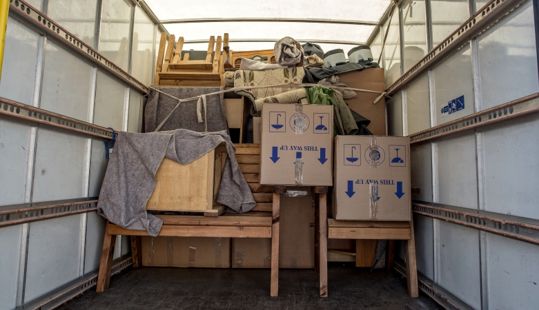 View inside an efficiently loaded box truck. The truck is loaded a little less than halfway with furniture and boxes. They’re tied down and secured so they won’t move in transit.