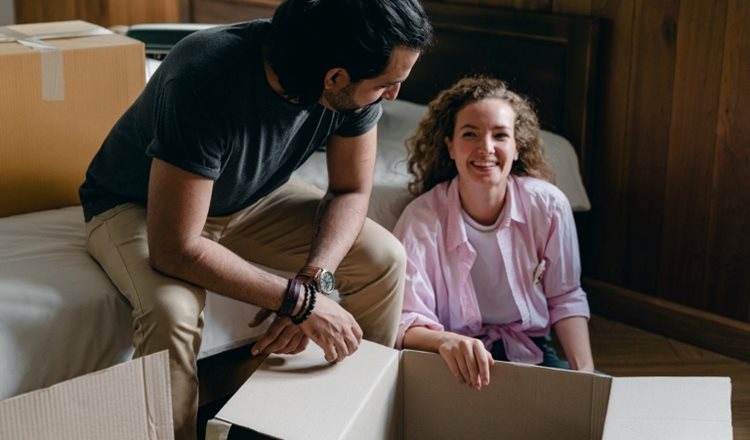 A happy couple is packing up moving boxes.