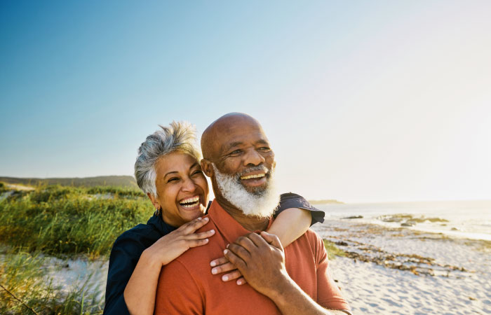 A happy, senior couple is watching the sunset on a beach in their new retirement state.