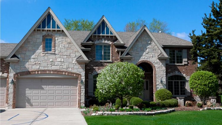 A beautiful single-family, new-construction home in Boerne, Texas. The home features three gables, and the exterior is alternately adorned with stone and brick. There is a two-car garage and a small path leading to the covered front door. The yard features decorative landscaping, including a couple of small trees and one mature pine.