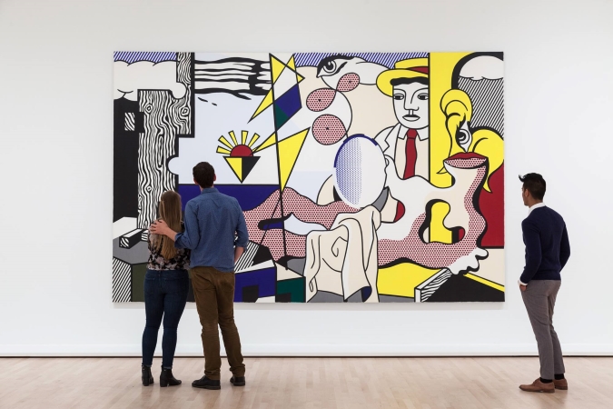 Three visitors are standing still, admiring a colorful piece of modern art at the San Francisco Museum of Modern Art. 