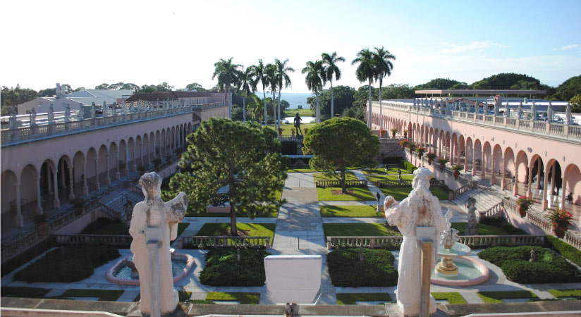 View from behind two classical statues looking out across The promenade at The Ringling, the official State Art Museum of Florida.