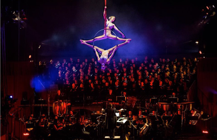 Two acrobats performing in the air, with the crowd and orchestra beneath them at The Circus Arts Conservatory in Sarasota, Florida.