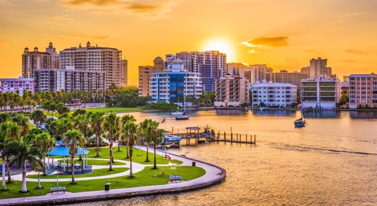 As the sun sets behind a slew of condo buildings, pink-orange light reflects off the harbor waters of Sarasota, Florida — one of the best places to live in Florida.