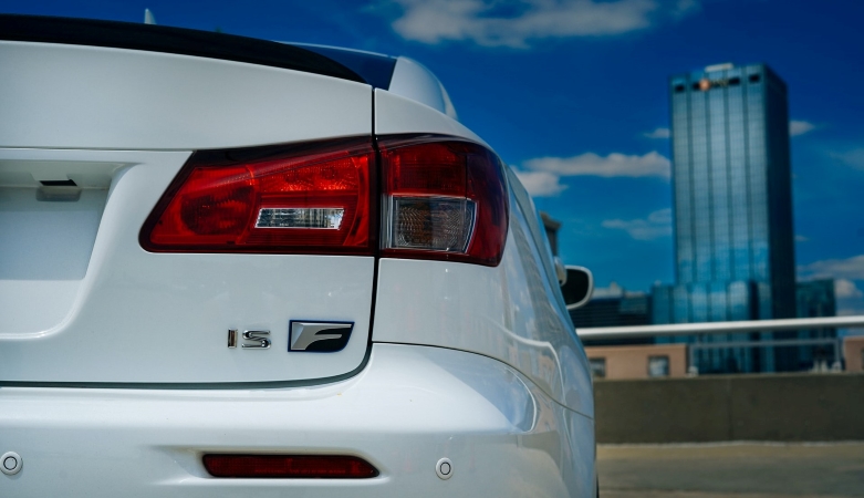 A close-up view of the right bumper and rear light of a white car with a Tampa, Florida, skyscraper in the background. 