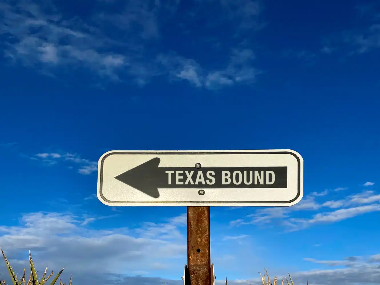 A road sign with a large black arrow and white lettering that reads "Texas Bound" is pointing the way to the best places to live in Texas.