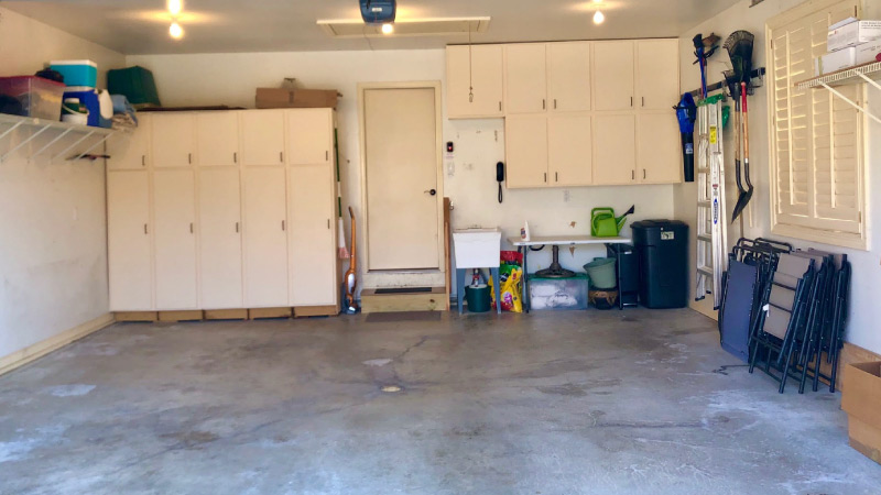 The after picture of a garage that was recently cleaned and decluttered. The storage cabinets are closed, chairs are neatly stacked against the wall, and everything has a place. The floor is clear of clutter.