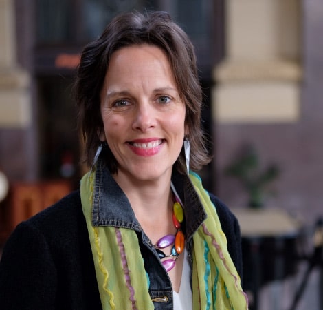 A headshot photograph of professional organizer Maija Diethelm. She’s smiling and wearing colorful jewelry and a scarf.