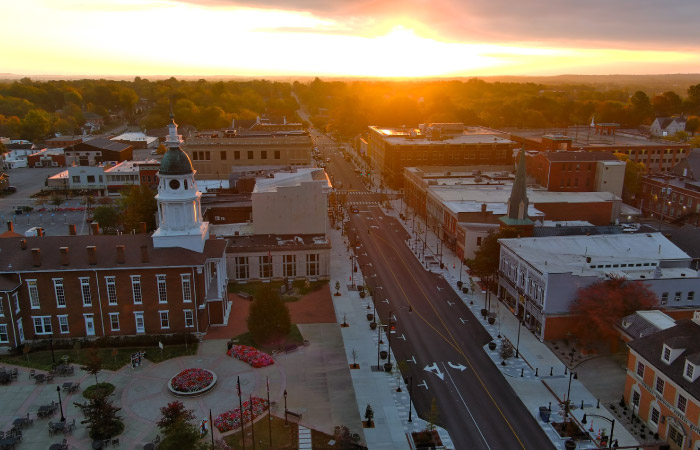Aerial view of Danville, Kentucky, during sunset. Many of the city’s buildings are made of red brick, and the downtown is surrounded by lush greenery.
