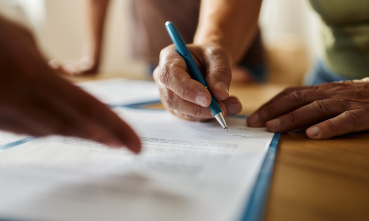 Close-up of someone signing the paperwork during a house closing.