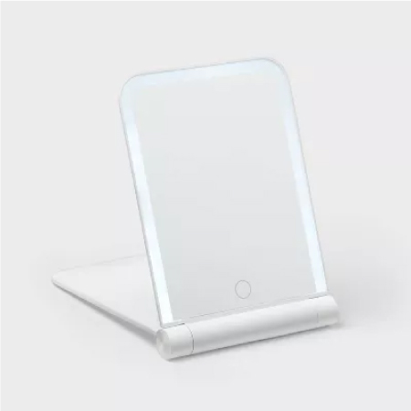 A folding vanity mirror on a white sink top