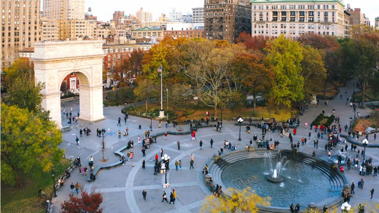 Aerial view of Washington Square Park in Greenwich Village, New York, on a summer day. There are dozens of people enjoying a cloudy autumn day in the park.