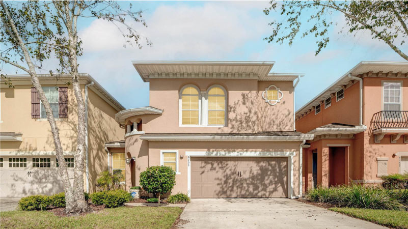 A two-story, Florida-style home in the Del Rio neighborhood of Jacksonville, Florida. The neighboring houses are built close by on either side.