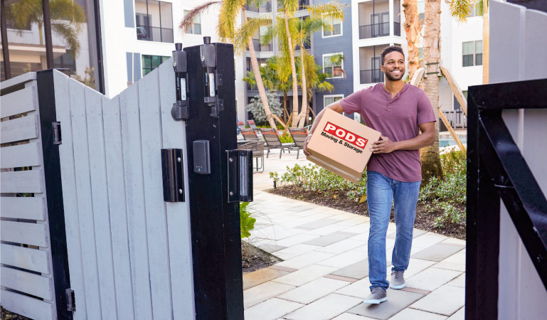 A man carrying a moving box through the pool area of his new apartment complex in Jacksonville, Florida.