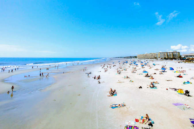 Beachgoers are relaxing on the sand and playing in the water at Folly Beach — one of the many perks of living in Charleston, SC