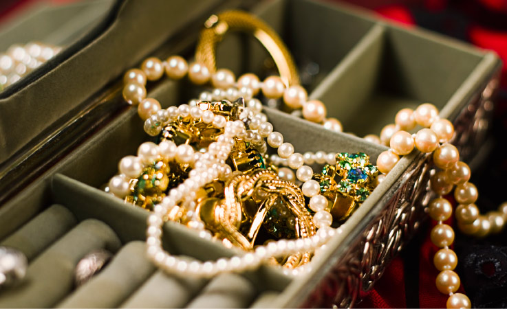 A close-up view of a jewelry box with pearls and various pieces of gold jewelry.