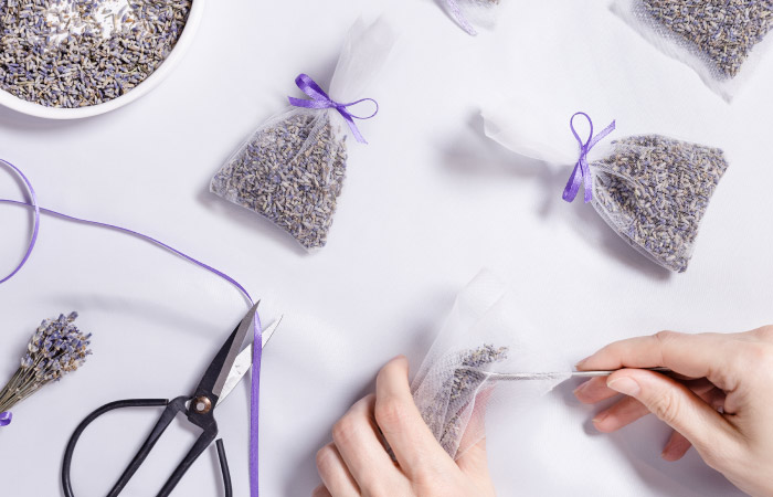 Close-up of a woman’s hands filling mesh sachets with dried lavender.