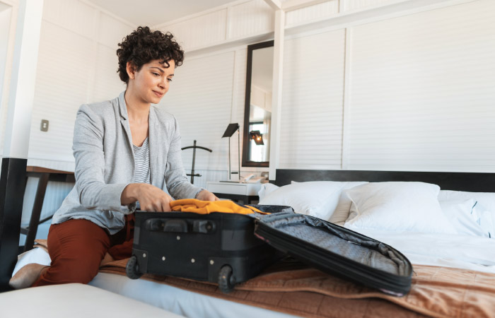 A woman is packing her suitcase with clothes that she’ll need immediately, so she doesn’t have to go digging through moving boxes during her move.