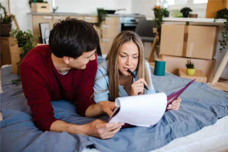 couple looking at list with moving boxes behind them