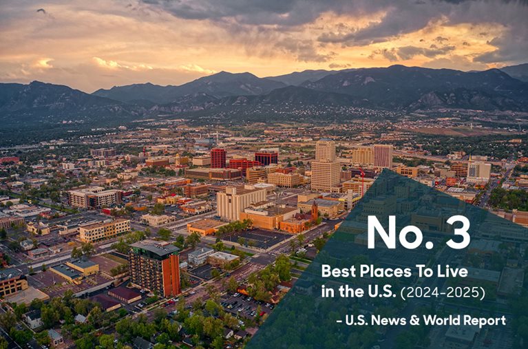 A drone’s view of the city of Colorado Springs in the early evening with overlaid text that reads “No. 3 Best Places To Live in the U.S. (2024–2025),” with an attribution to U.S. News & World Report.