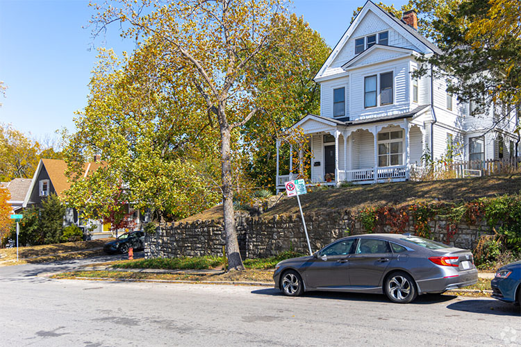  Craftsman home on a hilltop in Volker, Kansas City. Parked cars line the streets on a bright day.