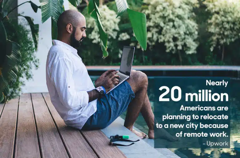 man sitting by pool working on a laptop