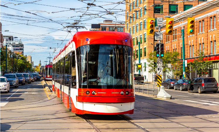 A red city cable car travels through Toronto city centre on a sunny day.