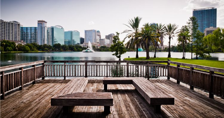 View of city buildings in one of the best neighborhoods in Orlando — Lake Eola Heights — from a wooden deck on a local lake