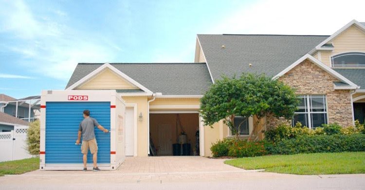 A man is about to raise the signature blue door on his PODS moving and storage container, positioned in his driveway. He’ll be using it to store things to make room for his upcoming half bath remodel.