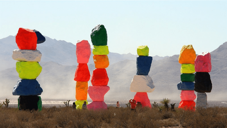 Tourists are taking pictures at the Seven Magic Mountains attraction outside of Las Vegas, Nevada. The large boulder stacks reach several stories high and each is painted in a unique series of vibrant colors.