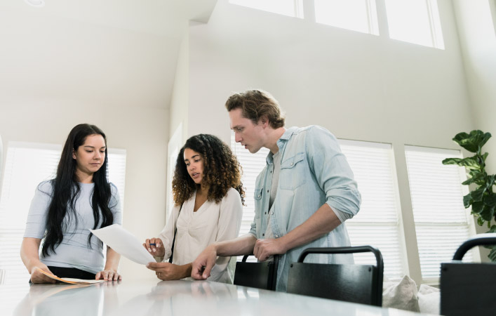 A couple is reviewing paperwork with a real estate professional in a conference room.