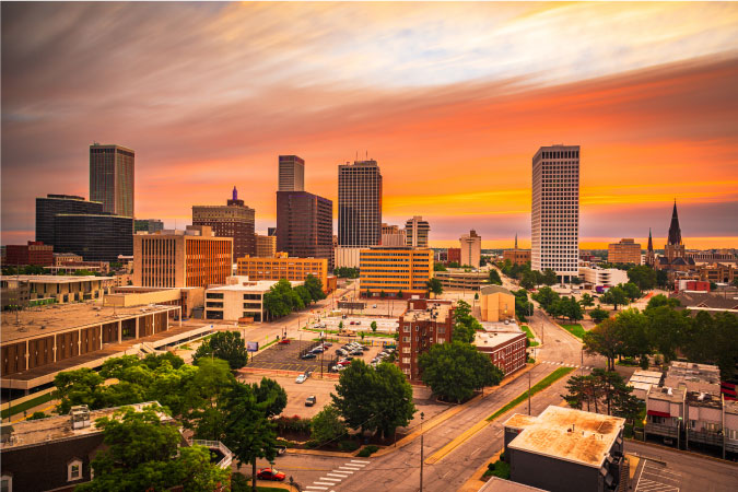 Sunset view of Tulsa, Oklahoma, with a vibrantly colored sky behind the tall city buildings