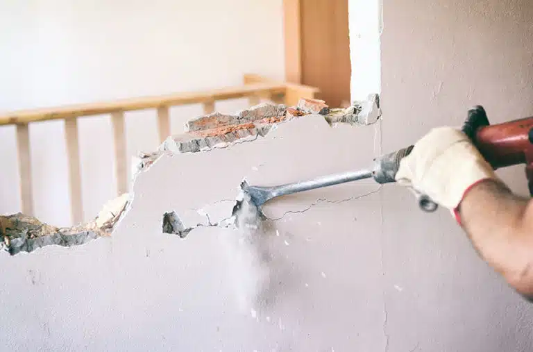man jackhammering interior wall