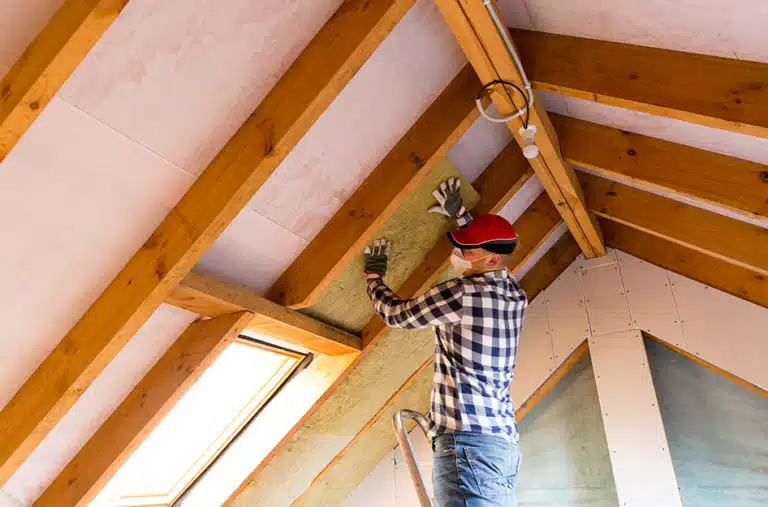 A man is wearing a dust mask as he works on his attic renovation.
