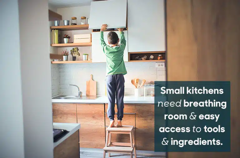 little boy standing on stool to get something from kitchen cabinet