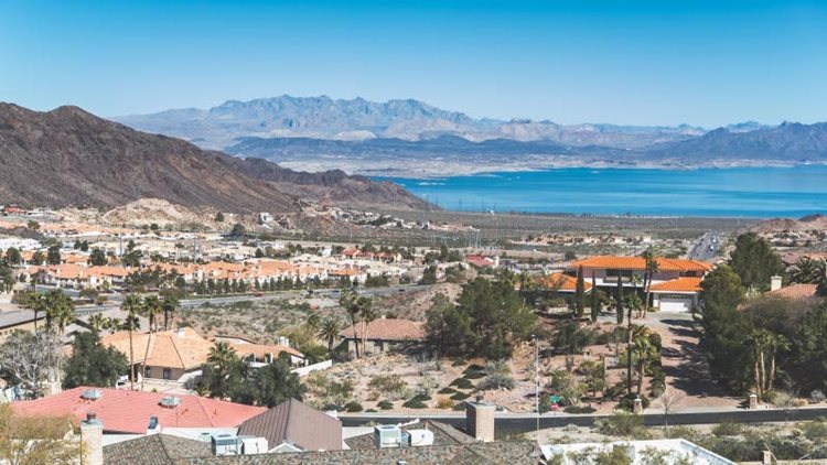 Aerial view of Boulder City, Nevada — a popular suburb near Las Vegas. A variety of residential homes of different styles make up the community, and locals enjoy views of a nearby lake and mountain range.