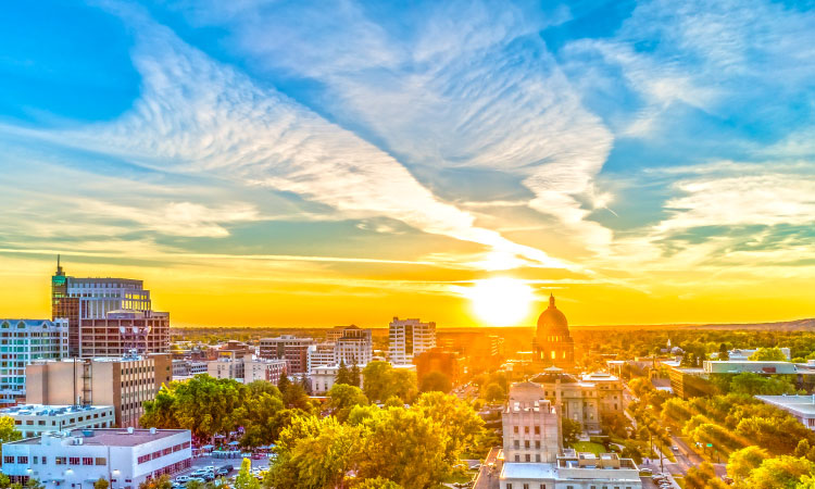 Aerial view of Boise, Idaho, during sunset. The sky is changing from blue to orange as golden rays of light stretch across the city skyline.