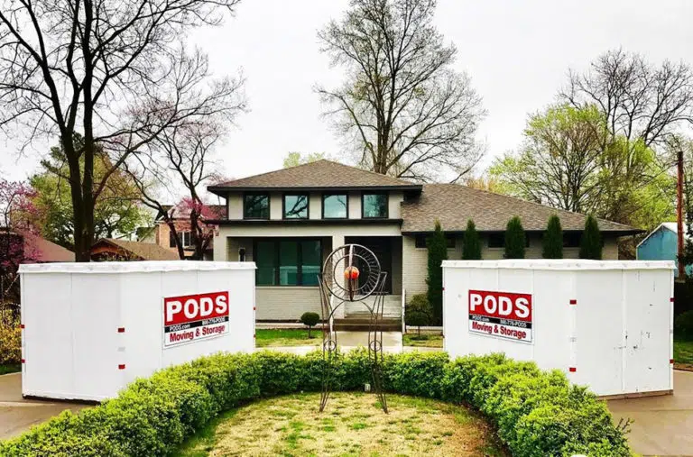 Two PODS containers sit in a half-circle driveway in front of a two-story home
