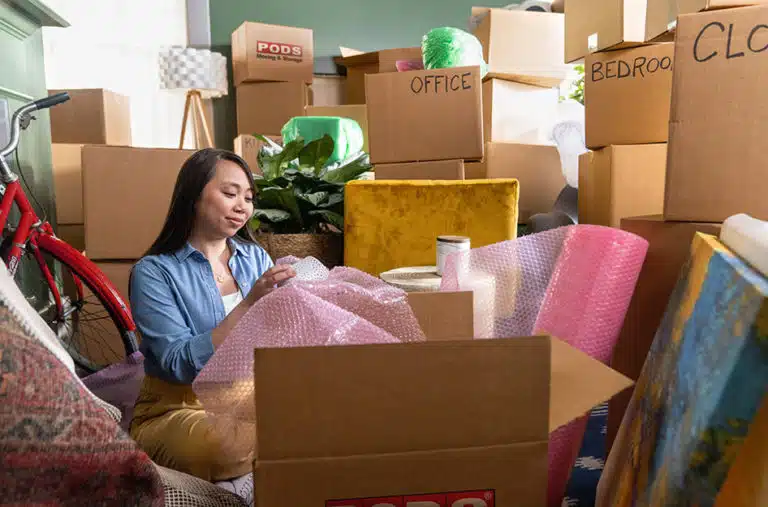 woman sitting among many moving boxes