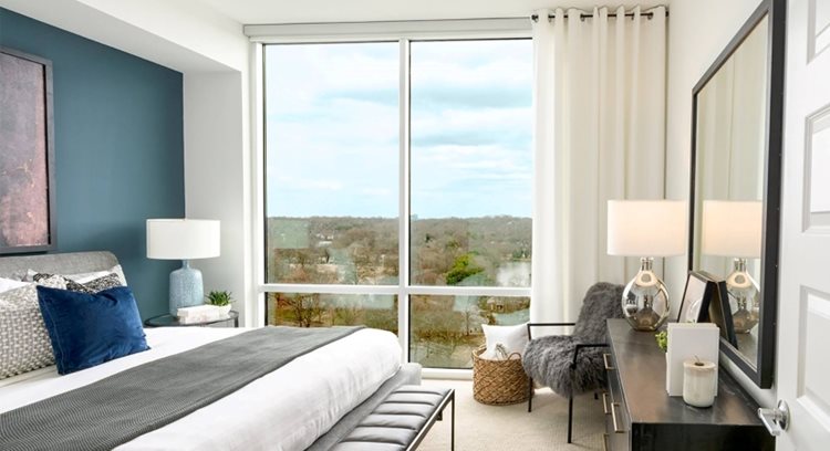 The interior view of a bedroom in one of Piedmont House’s apartments in Atlanta, Georgia. The room features a floor-to-ceiling window looking out over Piedmont Park.