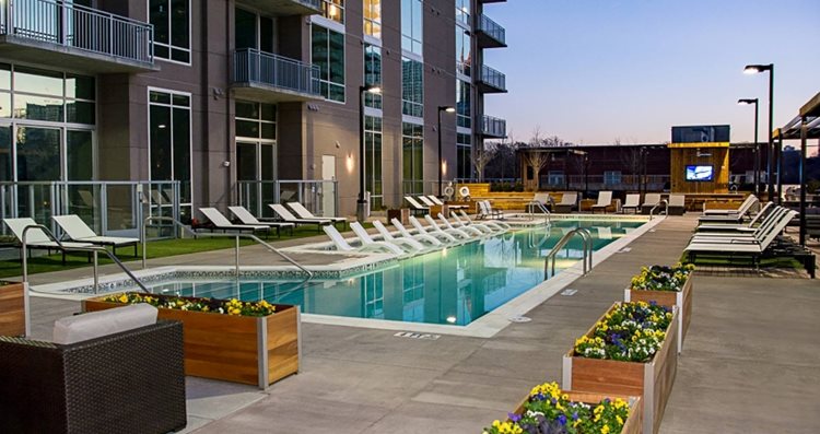 Deck-level view of the community pool at Piedmont House in Atlanta, Georgia. The patio features over two dozen reclining chairs and raised flower beds. 
