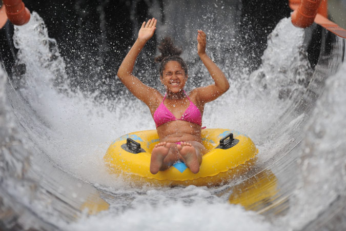  A young girl gets splashed by stationary water hoses as she rides down a water slide at Six Flags White Water in Marietta, Georgia.