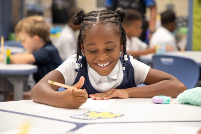 A happy kindergartener works on a writing assignment during class in a school in Marietta, Georgia.