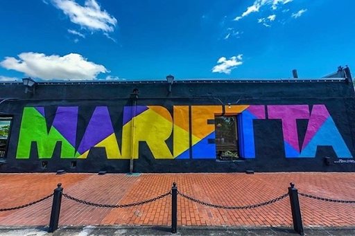 A colorful mural with the word “MARIETTA” painted in block letters against a black background on the side of a building in Marietta, Georgia. 