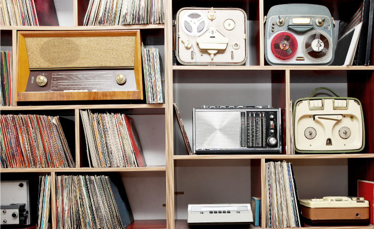 Close-up view of a bookcase that houses a collection of different vintage stereos, audio equipment, and records — all of which are sensitive to heat and humidity.