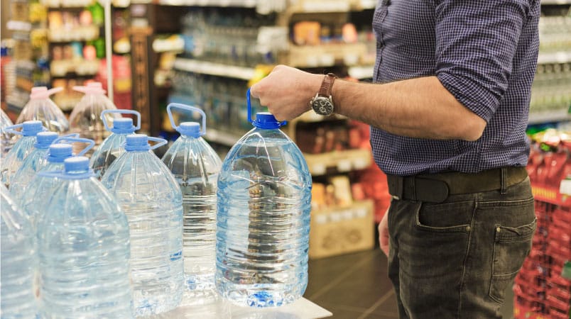 A man is at the grocery store, buying multiple gallons of water in preparation for a hurricane in Central Florida.