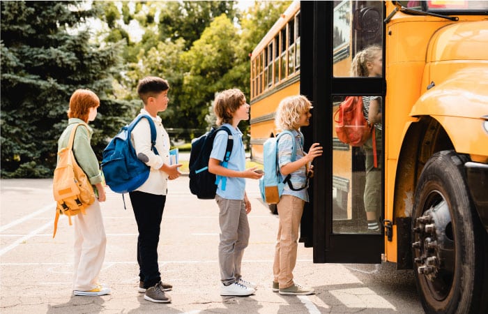A group of kids is waiting in line to board a public school bus on a sunny day in Portland, Oregon. 