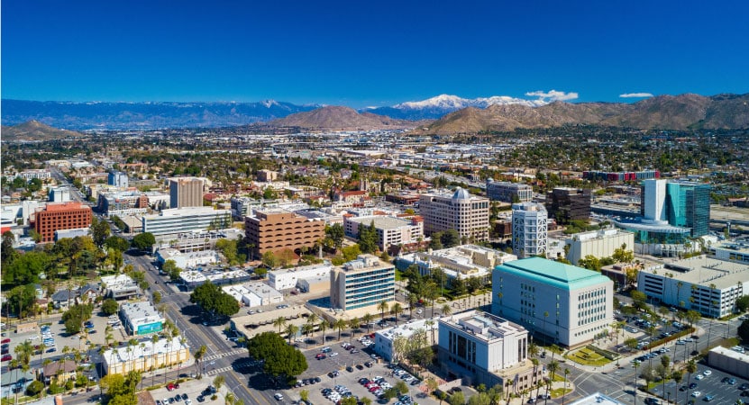 Aerial view of the city of Riverside, California. You can see the mountains in the background and the sky is a clear blue.