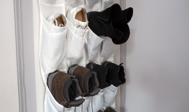 A white over-the-door hanging shoe organizer holding different types of shoes.