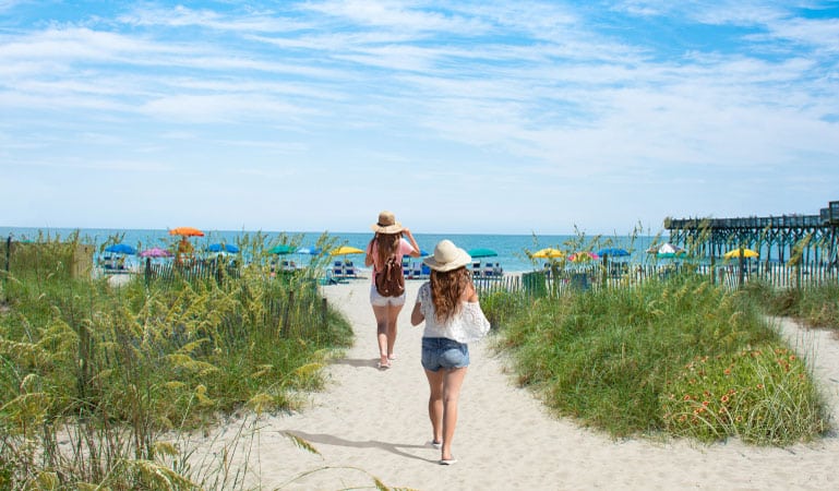Two women walk toward the beach